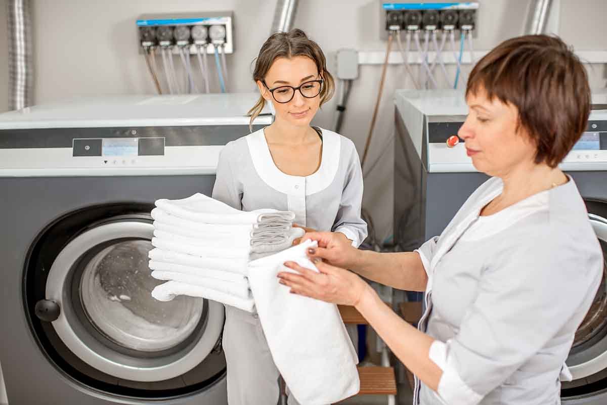 senior washwoman with young assistant in the commercial laundry location