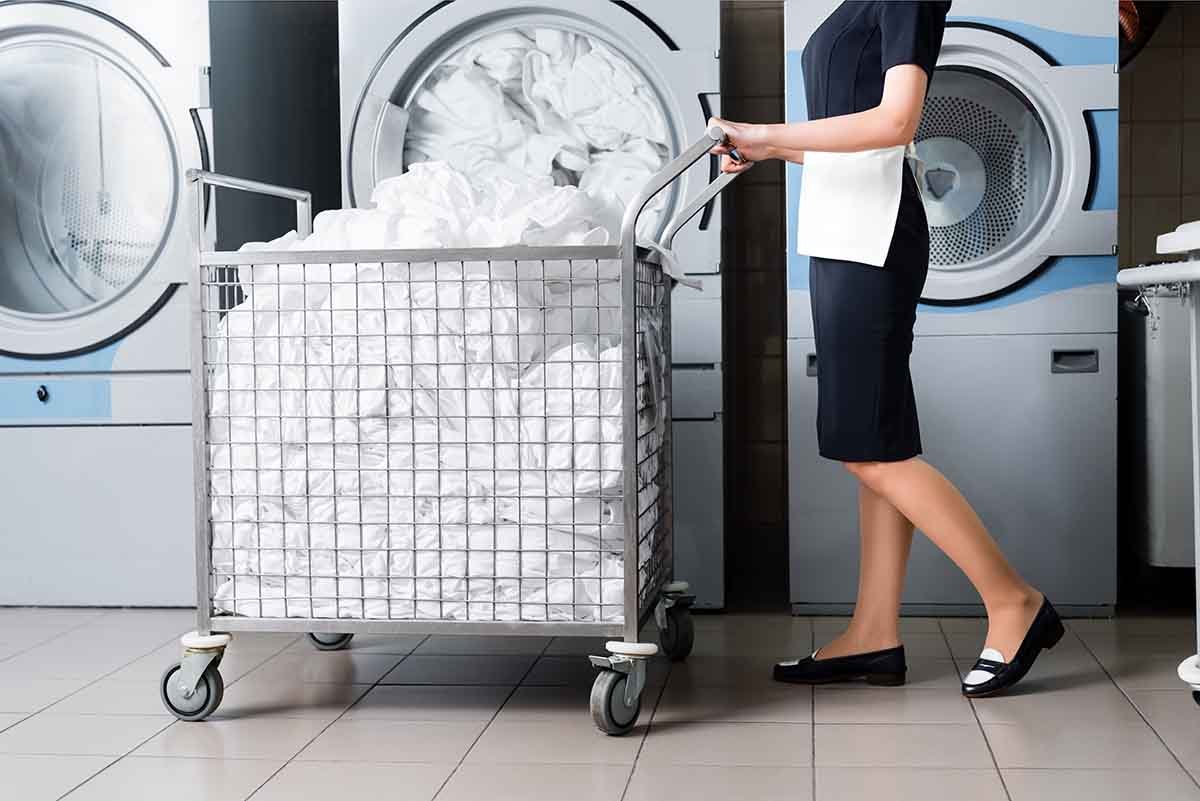 worker pushing laundry cart in commercial laundry facility